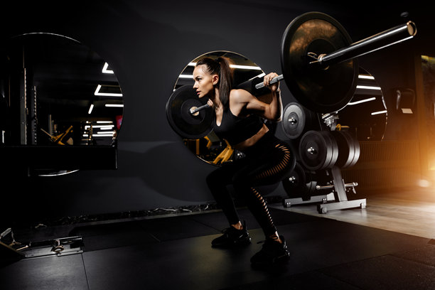 健身房里，一位强大的女性正在进行深蹲训练，举着重型杠铃的广角照片图片下载