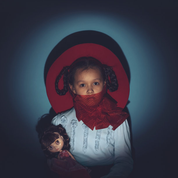 戴着红色帽子和红色丝带的孩子手里抱着一个玩偶的艺术照片图片下载