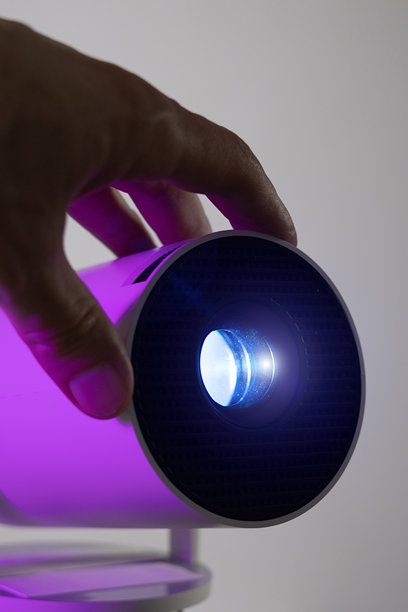 男子的手在调整现代Wi-Fi视频投影仪的镜头，蓝色灯光照射。适合视频或照片展示和家庭电影观看。图片下载