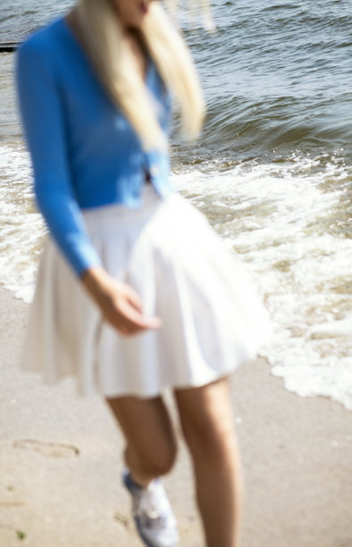 模糊的照片。美丽的女孩在阳光明媚的天气里沙滩上奔跑。图片下载