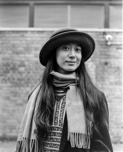 年轻女性戴着帽子和围巾，在单色胶卷照片中微笑图片下载