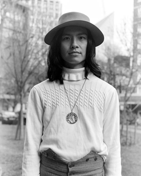 年轻男子戴着帽子和吊坠，在单色胶卷照片中摆姿势图片下载