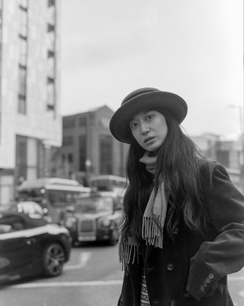 年轻时尚的女性在城市环境中佩戴帽子和围巾，颗粒感黑白胶卷照片图片下载