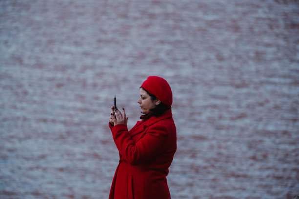 穿着红色外套的女人用手机拍摄海洋的照片图片下载
