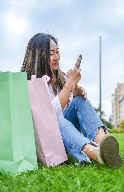 年轻女性在城市公园拍摄购物袋的照片图片下载