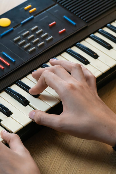 女性双手特写，熟练地演奏电子键盘，突显音乐创作的精妙艺术和驱动音乐表达的热情。竖版照片图片下载
