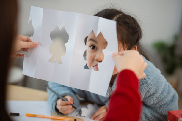亚洲儿童在家中进行创意活动，使用剪纸和绘画工具图片下载