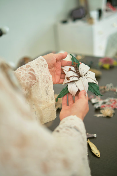 一位穿着蕾丝服装的造型师仔细查看桌子上的各种珠宝饰品。照片突显了时尚造型和配饰选择的细致与创意过程。图片下载