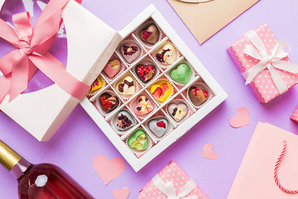 情人节装饰购物的俯视照片，包含购物袋、酒瓶、信封、礼物盒、糖果和红心，背景为彩色，留有空白空间。框架背景。图片下载