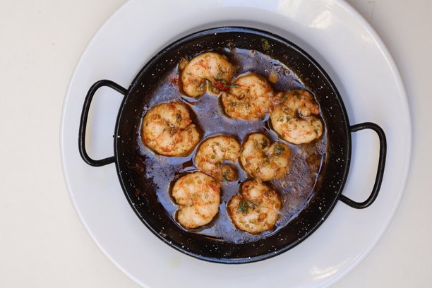 西班牙菜肴伽巴斯皮尔皮尔，传统铸铁锅盛装，白色盘子放在桌面上的俯视照片图片下载