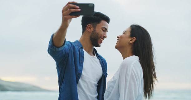 海滩，情侣在蜜月、假期或户外亲密时刻快乐自拍，女人和男人在海边留下美好回忆，浪漫约会，开心地在社交媒体上分享个人资料照片。图片下载