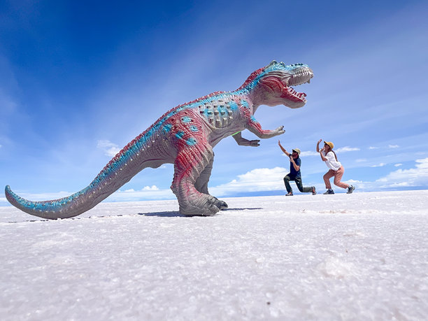 创意视角照片：人们假装逃跑于玩具恐龙的场景图片下载