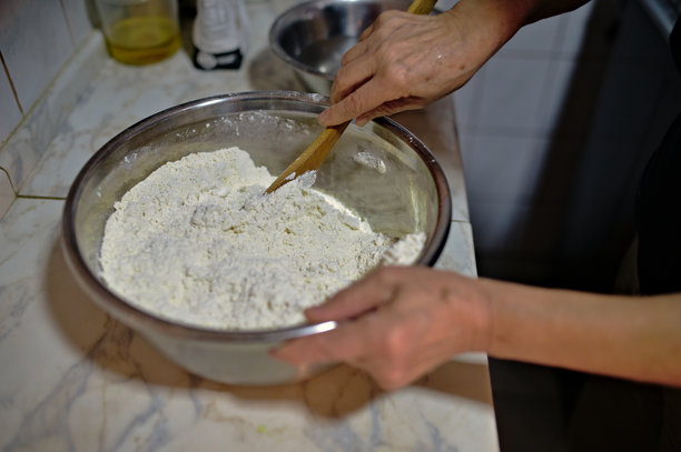 一位女性在揉面团以制作发酵面包，然后将其放入电烤箱中烘烤的照片图片下载