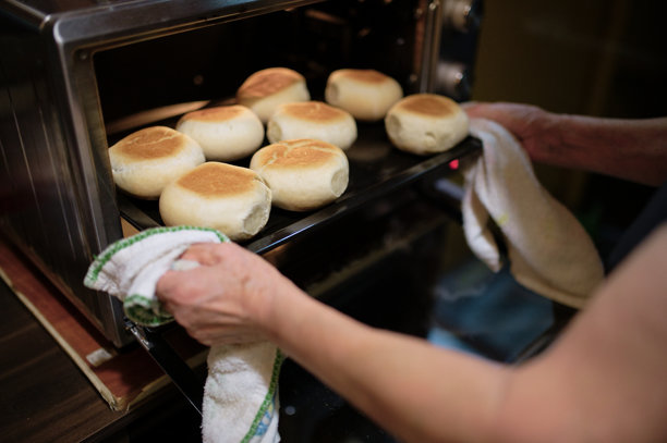 一位女性在揉面团以制作发酵面包，然后将其放入电烤箱中烘烤的照片图片下载
