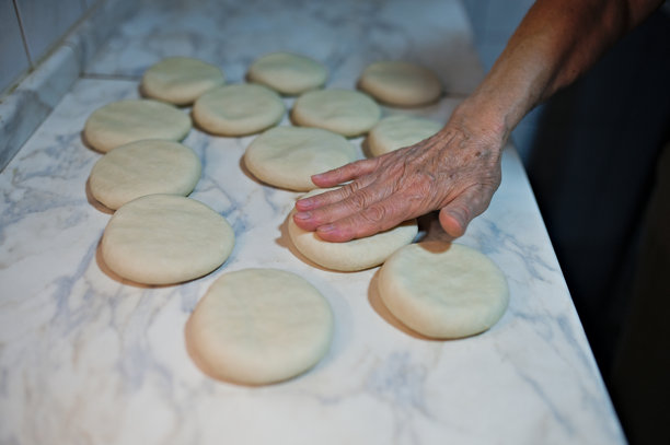 一位女性在揉面团以制作揉面包，然后将其放入电烤箱中烘烤的照片图片下载