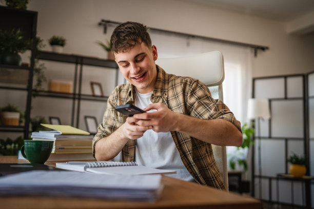 年轻男学生在家学习时拍摄笔记照片图片下载