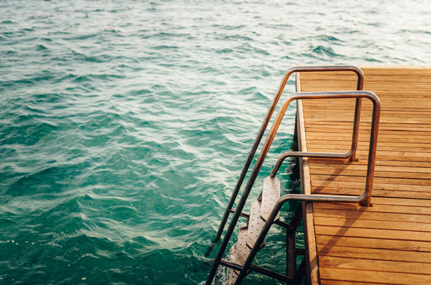 木质甲板和金属梯子通向碧蓝的海洋。夏季假期照片图片下载