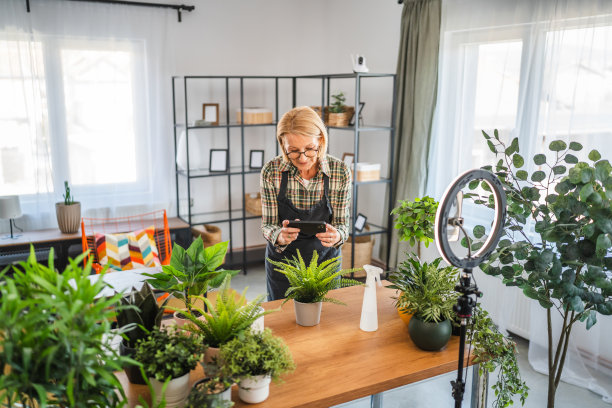 成熟的女性使用手机拍摄家中植物的照片或视频图片下载