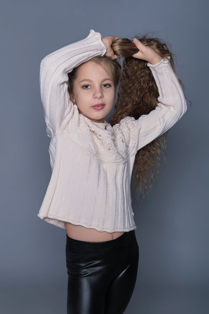 一个女孩用手穿过她的长发，展现出自然的美丽和活泼的自信。这张照片反映了保持儿童健康头发的重要性，提倡对护发习惯的积极态度。图片下载