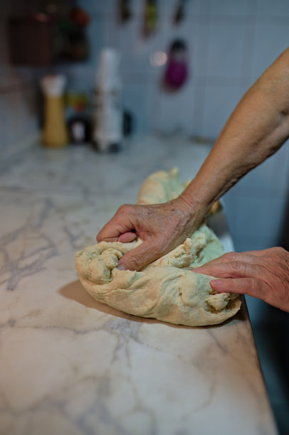 一位女性在揉面团以制作揉面包，然后将其放入电烤箱中烘烤的照片图片下载