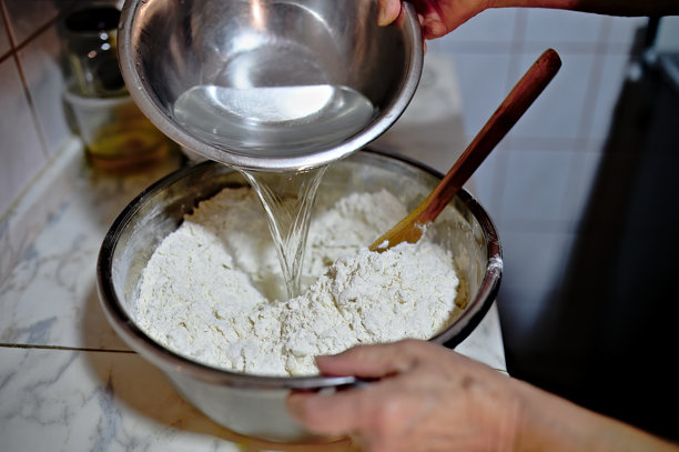 一位女性在揉面团以制作发酵面包，然后将其放入电烤箱中烘烤的照片图片下载