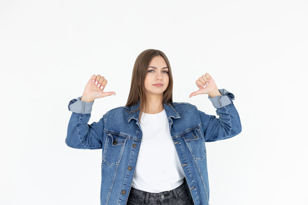 特写照片，惊艳的美丽女士竖起大拇指，表示自信，传达“我是最佳选择，请选择我”的信息，穿着休闲的白色T恤和牛仔外套，背景为纯白色。图片下载