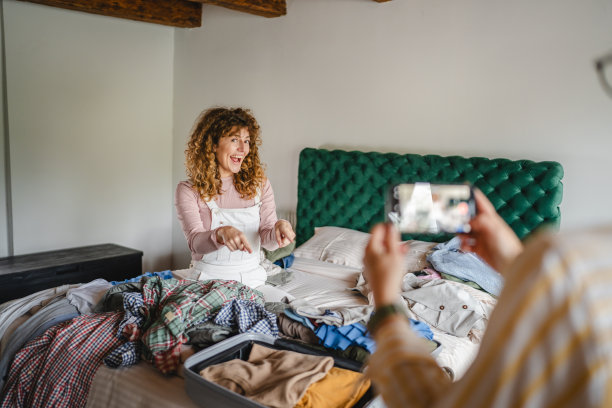 母亲使用手机拍摄女儿收拾行李的视频和照片图片下载