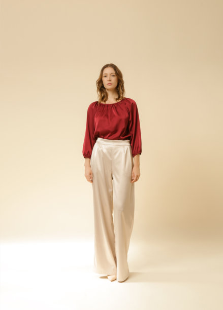 一系列年轻女性模特在摄影棚中穿着简单的丝绸缎美丽服装，酒红色上衣和米色宽腿裤的照片。图片下载