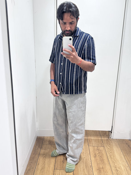 男子在更衣室试穿衣服和牛仔裤 / 时尚模特自拍作为个人资料照片 / 时尚男士在更衣室探索服装搭配图片下载