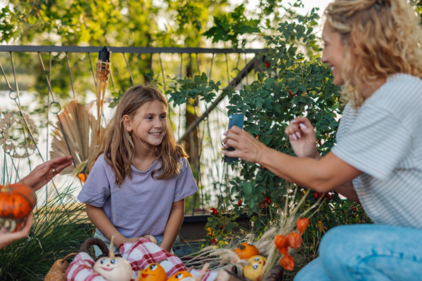 母亲在花园里拍摄女儿与万圣节南瓜装饰的照片图片下载