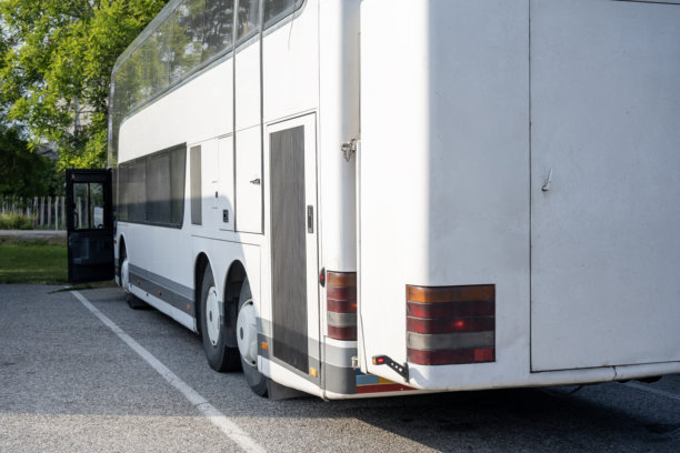 一辆白色公交车停在停车场，正在等待乘客上车。照片是从后面拍摄的。图片下载