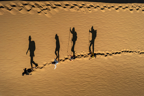 日落时分沙漠中行走的剪影航拍照片图片下载