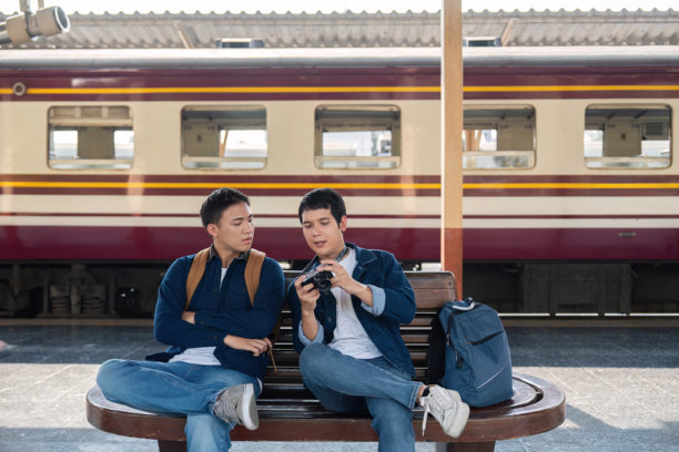 捕捉回忆与旅行中的情谊。两个朋友坐在一起回顾他们的旅行照片。图片下载