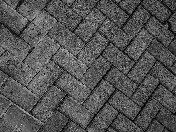 黑白照片展示了以人字形图案排列的砖铺地面纹理，细节粗犷。图片下载