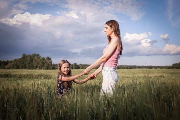 母女在美丽的田野中玩得开心。春夏摄影。快乐的童年，幸福与欢笑。母爱的关怀。照片的主题是母亲节和儿童节。图片下载