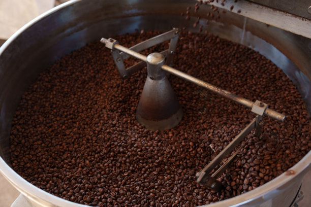 咖啡豆在大型金属鼓中烘焙的照片 - 阿拉比卡和罗布斯塔的混合，旨在生产具有优良口感的优质咖啡。图片下载