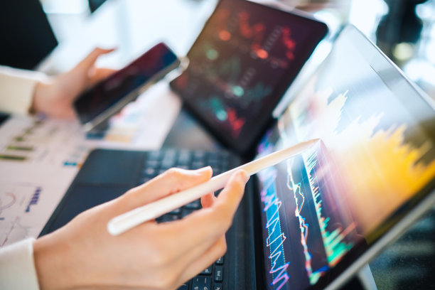 股票交易员指着高分辨率触摸屏上的实时市场数据，分析交易量和价格走势，使用互动金融仪表板。图片下载
