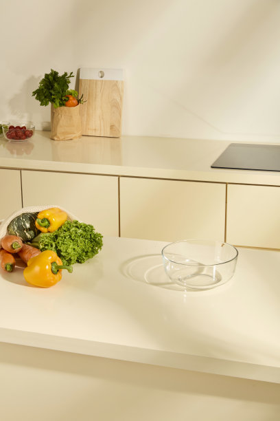 空的透明玻璃碗放在厨房台面上。新鲜的胡萝卜、甜椒和从农场收获的南瓜。温馨的厨房空间，充满自然光。用于设计关键视觉布局的照片。图片下载