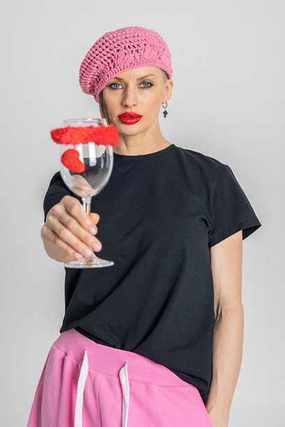 美丽的浪漫女孩戴着粉色贝雷帽，手中拿着装饰有红色心形图案的玻璃杯。选择性对焦。竖版照片。图片下载