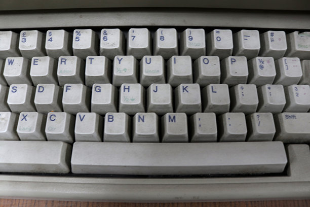 一台旧的、磨损的、布满灰尘的电脑键盘的照片图片下载
