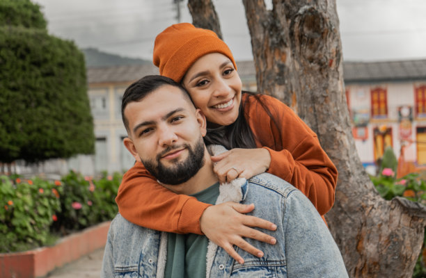 年轻情侣在色彩斑斓的村庄中拥抱微笑 - 股票照片。图片下载