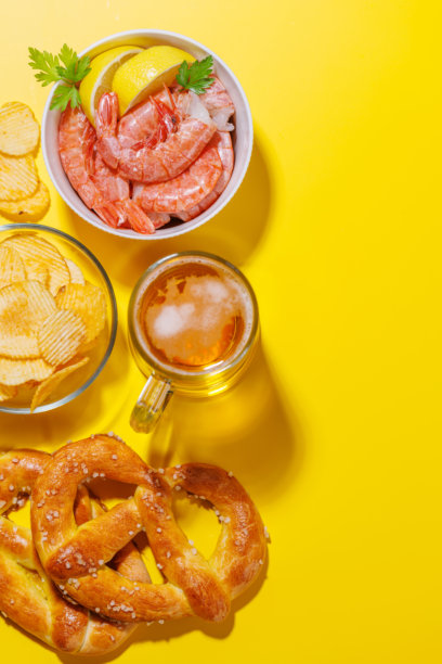 一张生动的照片，展示了一杯啤酒，周围是各种小吃和快餐。图片下载