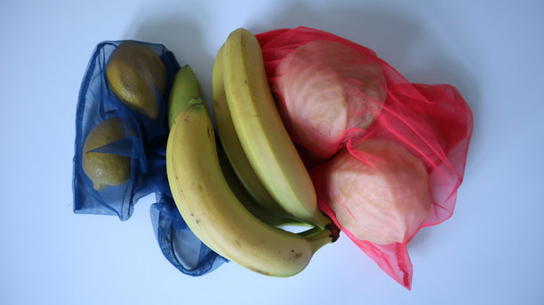 生态网袋中的水果和蔬菜照片。白色背景。两个柠檬、卷心菜和香蕉。图片下载