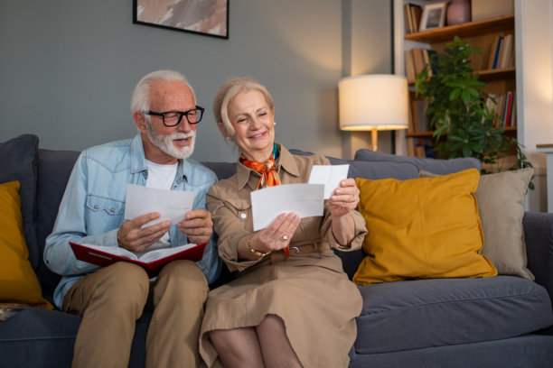 快乐的老年夫妇坐在沙发上翻看旧照片图片下载