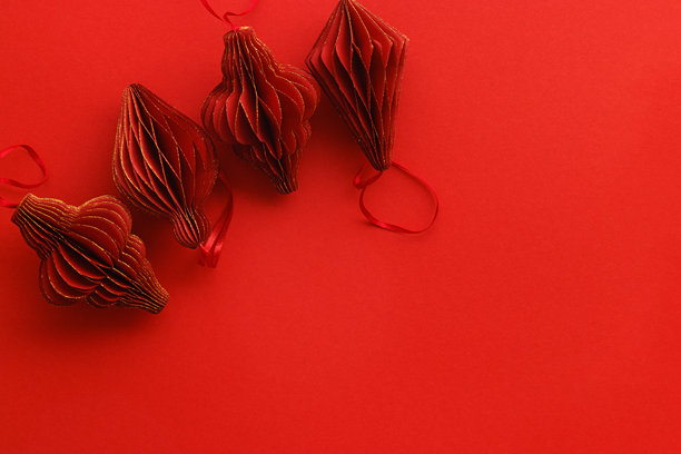 节日红色纸质圣诞装饰品，悬挂的红色手电筒，金色光辉的灯笼，红色背景上的极简美学单色照片，节日假日俯视平铺图案，留白空间图片下载