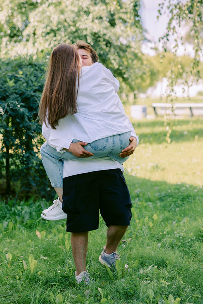 年轻情侣在温暖的夏日里，在公园里散步并享受快乐时光。竖版照片图片下载