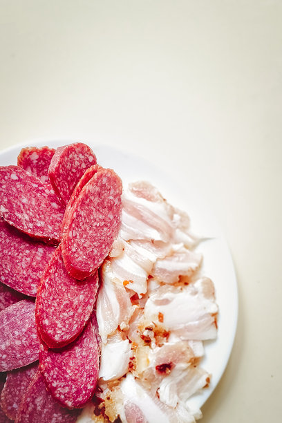 切片的熏香肠和培根放在中性背景上。竖版照片。图片下载