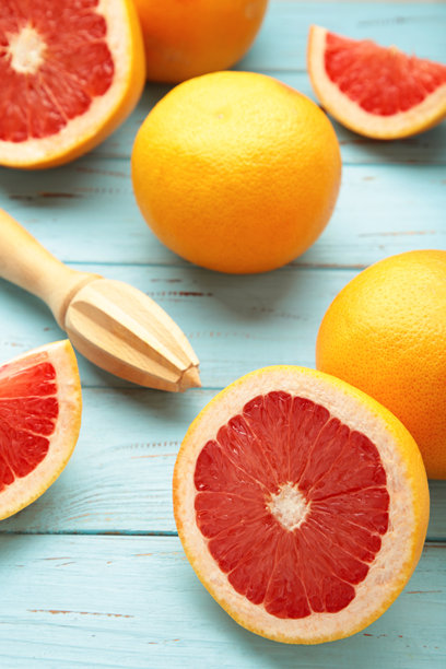 新鲜有机葡萄柚和木制榨汁器在蓝色背景上，俯视图。竖版照片图片下载