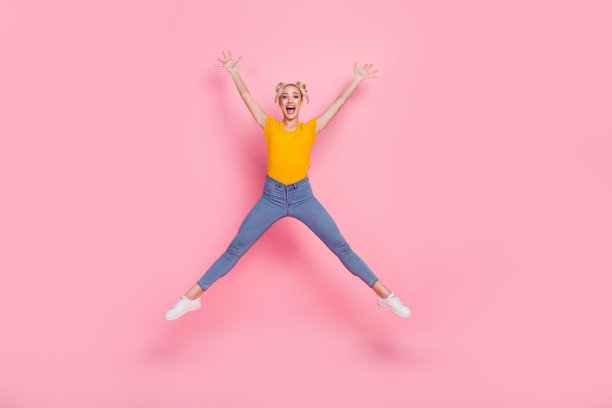 全身照片，快乐、欢笑、兴奋的疯狂女孩在粉色背景上跳起星星姿势，享受自由时光。图片下载