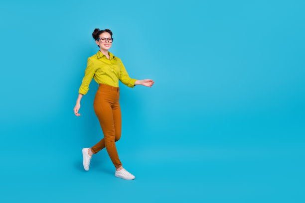 充满活力的年轻人在蓝色背景下的空旷空间中行走的全身照片图片下载
